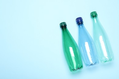 Photo of Plastic bottles on light background, top view. Space for text