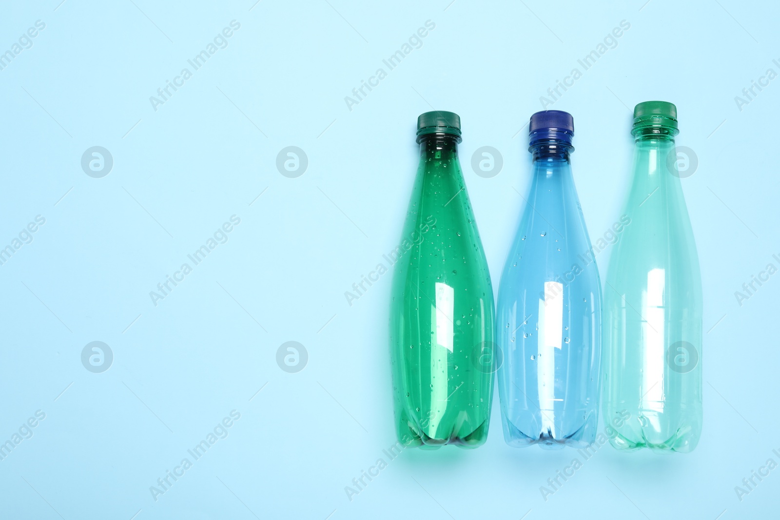 Photo of Plastic bottles on light background, top view. Space for text