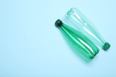 Photo of Plastic bottles on light background, top view. Space for text