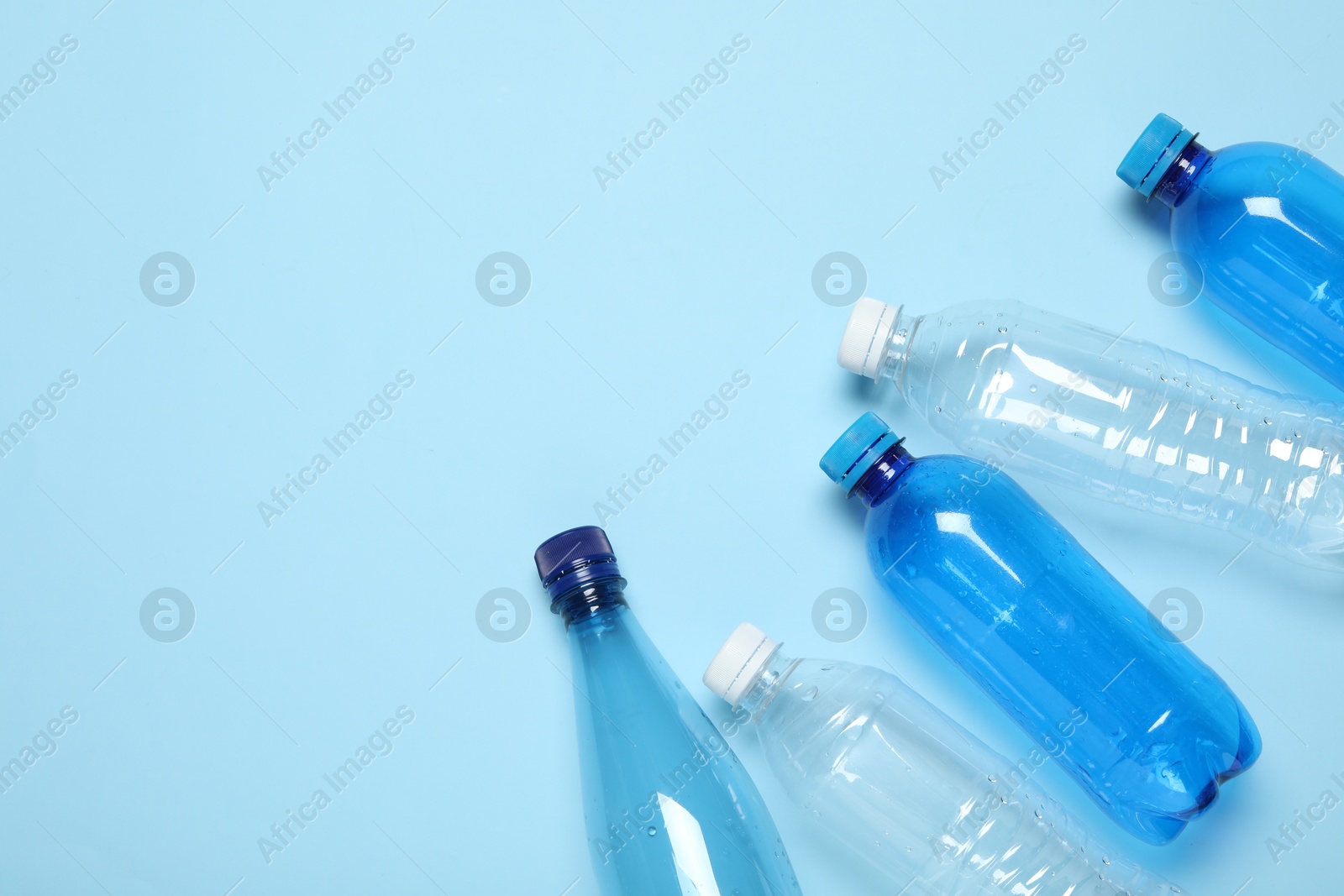 Photo of Plastic bottles on light background, top view. Space for text