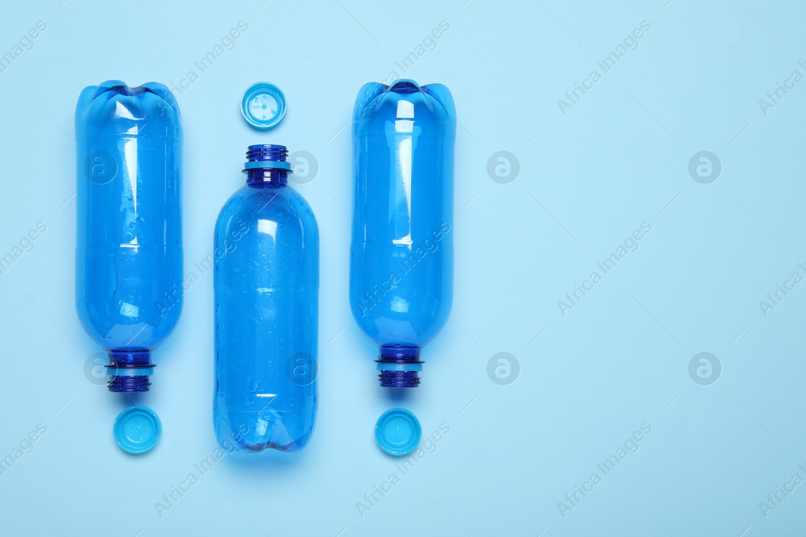 Photo of Plastic bottles and caps on light background, top view. Space for text