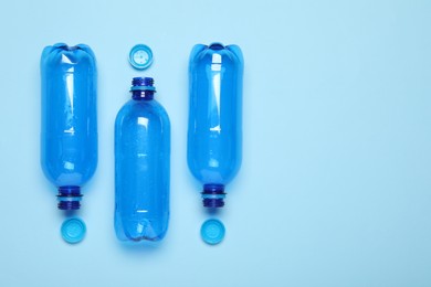 Photo of Plastic bottles and caps on light background, top view. Space for text