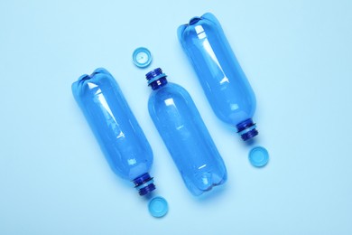 Plastic bottles and caps on light background, top view