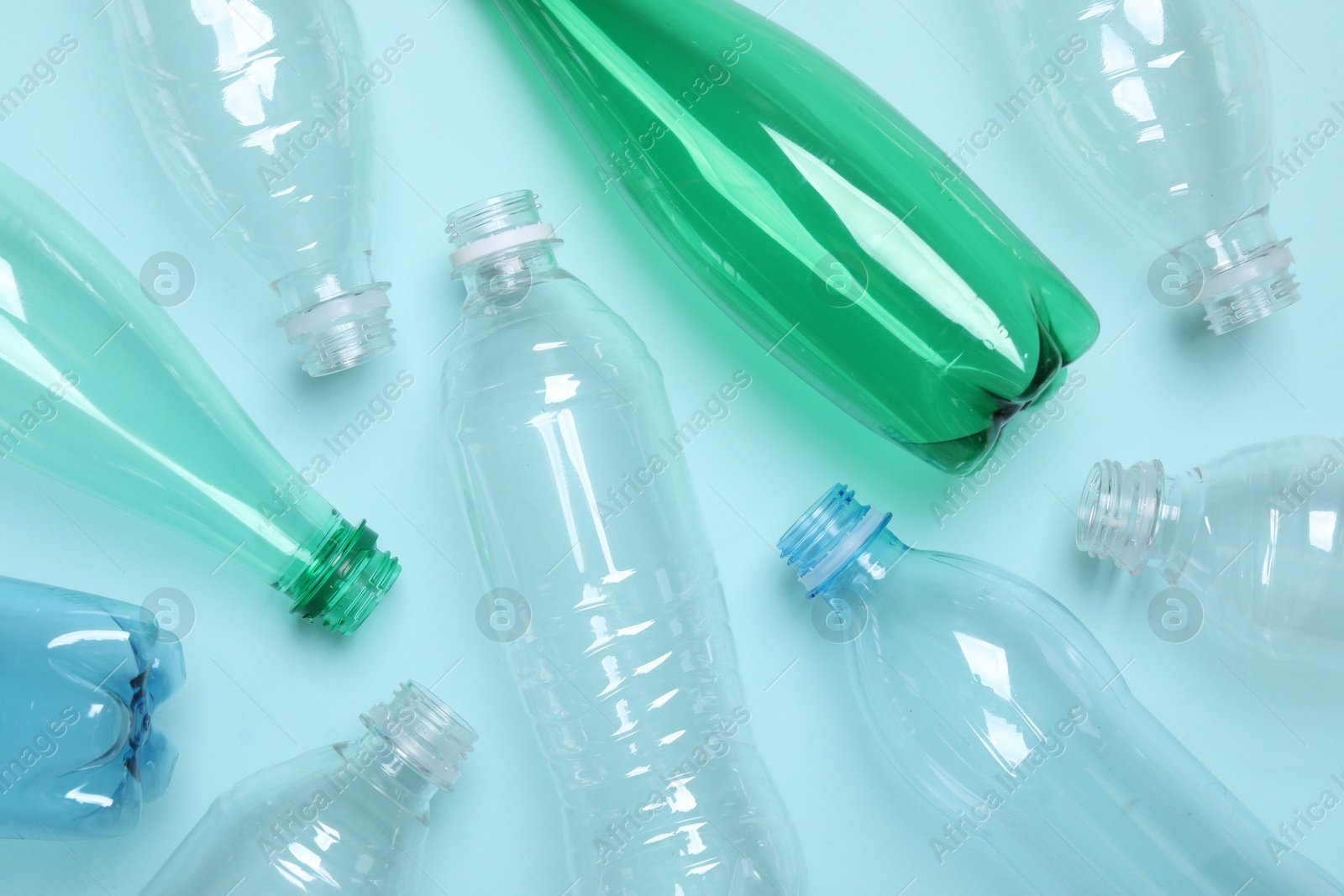 Photo of Empty plastic bottles on light blue background, flat lay