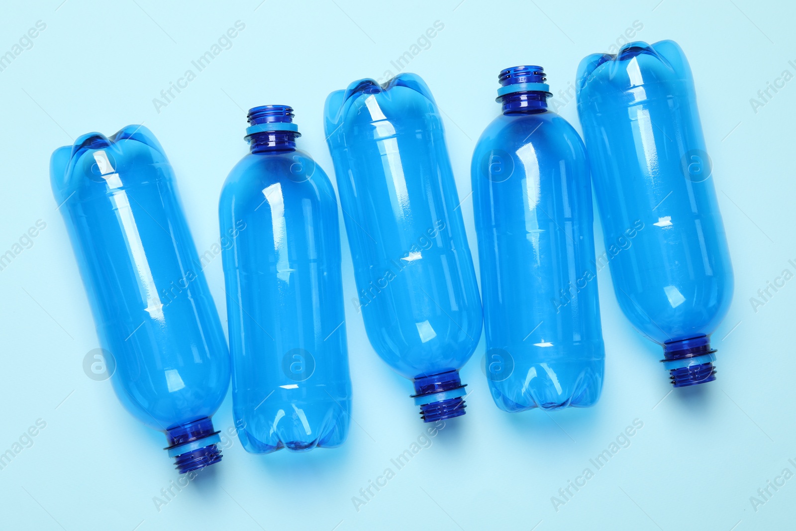 Photo of Empty plastic bottles on light blue background, flat lay