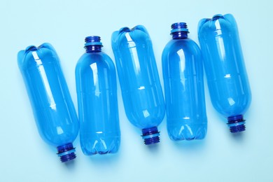 Empty plastic bottles on light blue background, flat lay