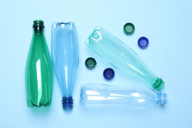 Empty plastic bottles on light blue background, flat lay