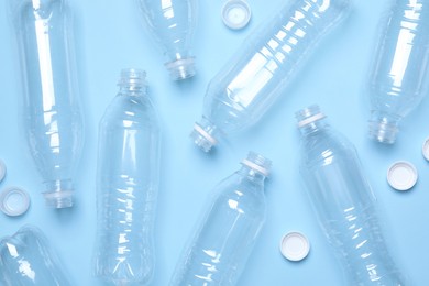 Empty plastic bottles on light blue background, flat lay