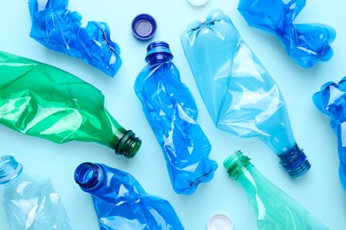 Crumpled plastic bottles on light blue background, flat lay