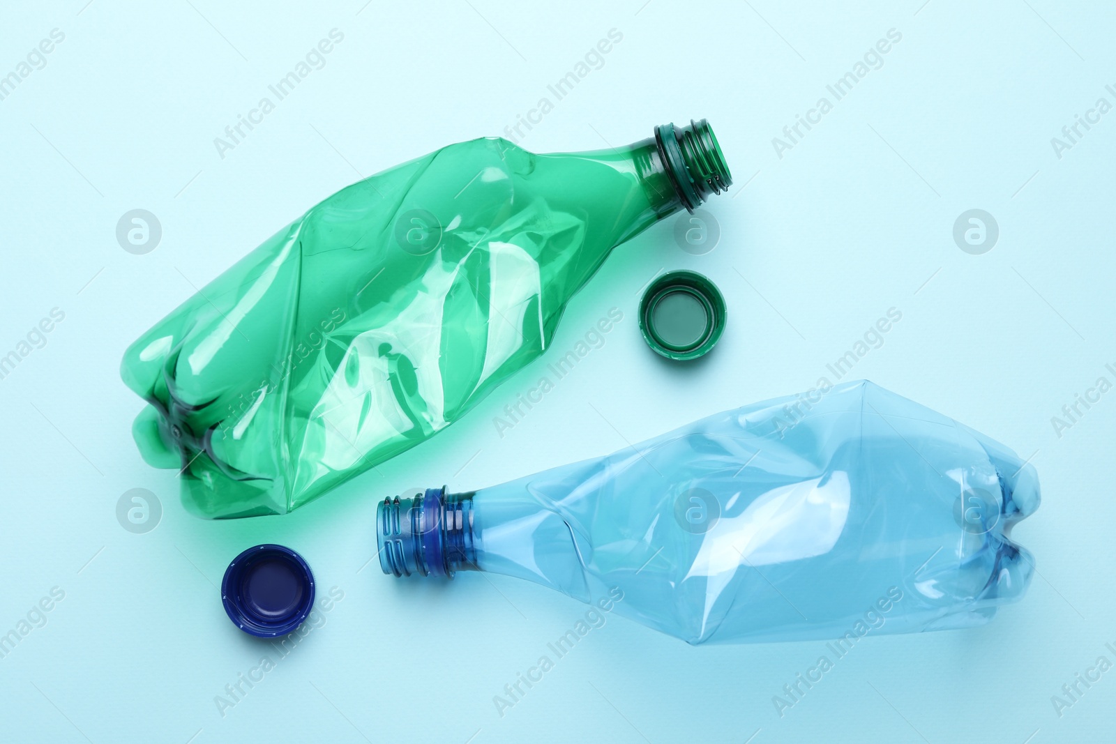 Photo of Crumpled plastic bottles on light blue background, flat lay