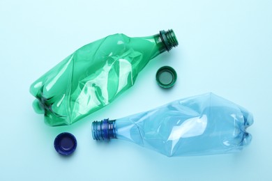 Crumpled plastic bottles on light blue background, flat lay