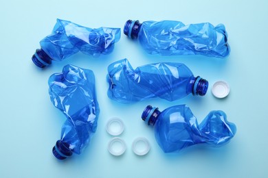 Crumpled plastic bottles on light blue background, flat lay