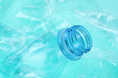 Photo of Crumpled plastic bottles on turquoise background, closeup