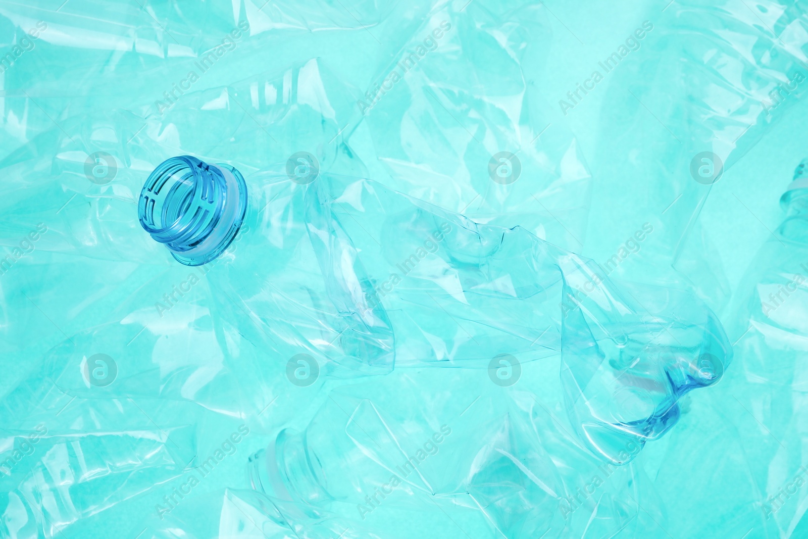 Photo of Crumpled plastic bottles on turquoise background, closeup