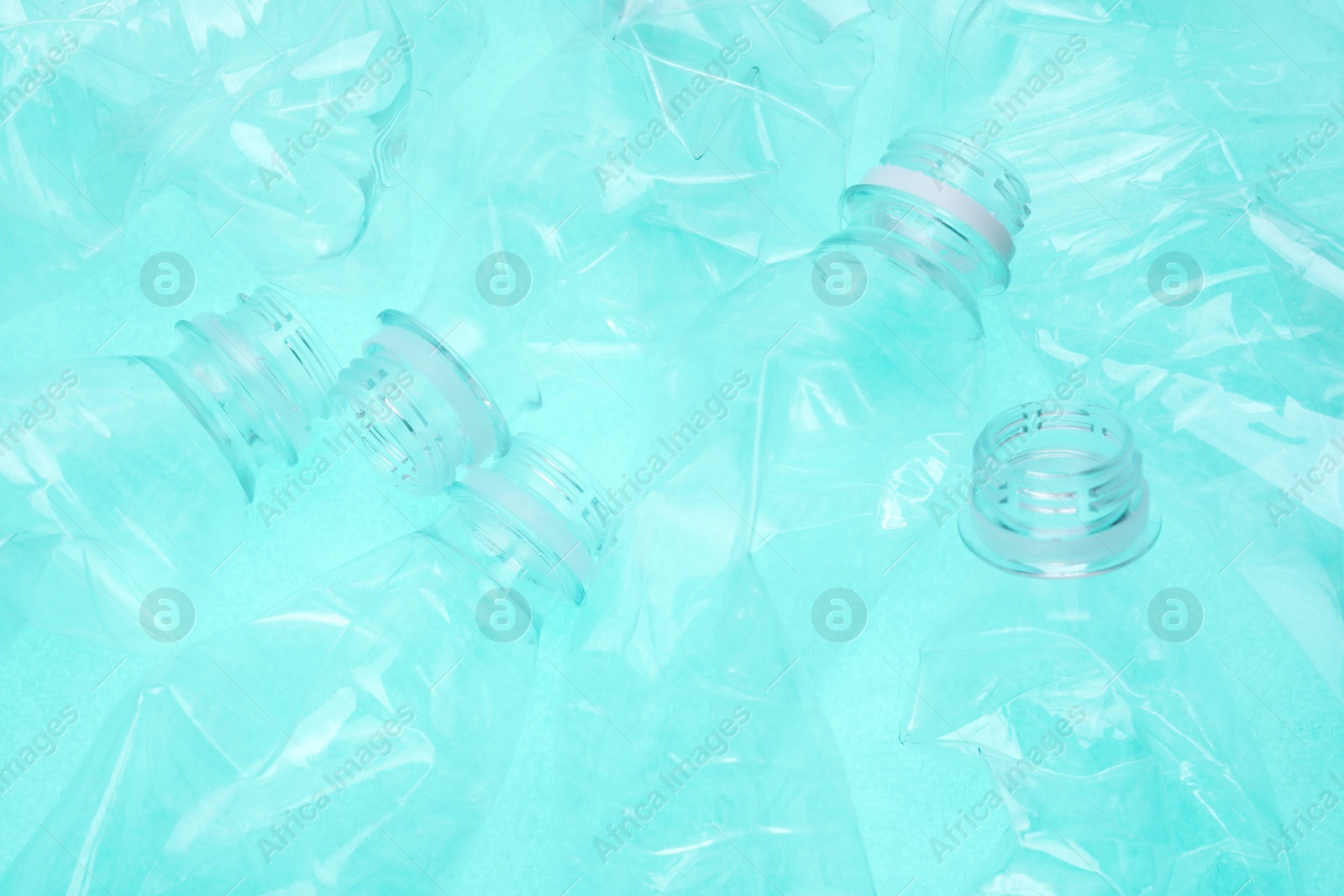 Photo of Crumpled plastic bottles on turquoise background, closeup