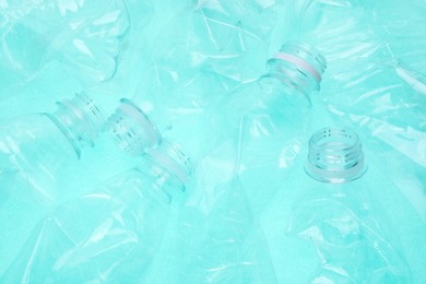 Crumpled plastic bottles on turquoise background, closeup