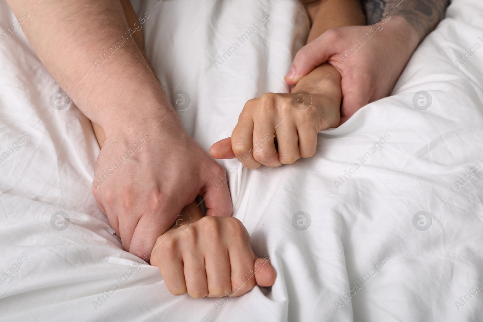 Photo of Lovely couple holding hands in bed, above view