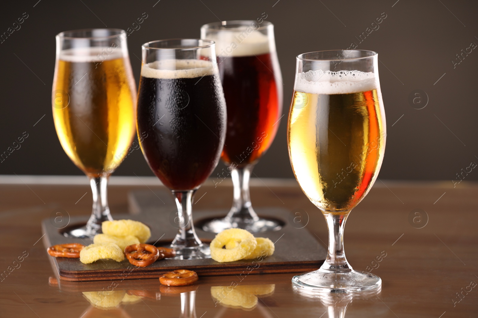 Photo of Glasses with different types of beer and snacks on table, closeup