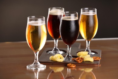 Photo of Glasses with different types of beer and snacks on table