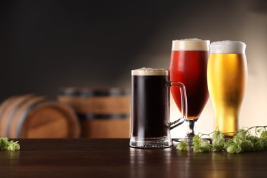 Photo of Glasses with different types of beer and fresh hops on wooden table in bar. Space for text