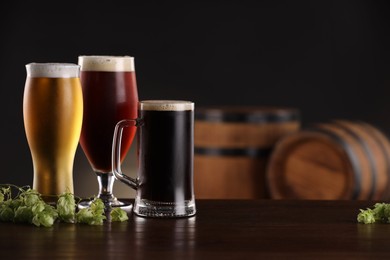 Photo of Glasses with different types of beer and fresh hops on wooden table in bar. Space for text