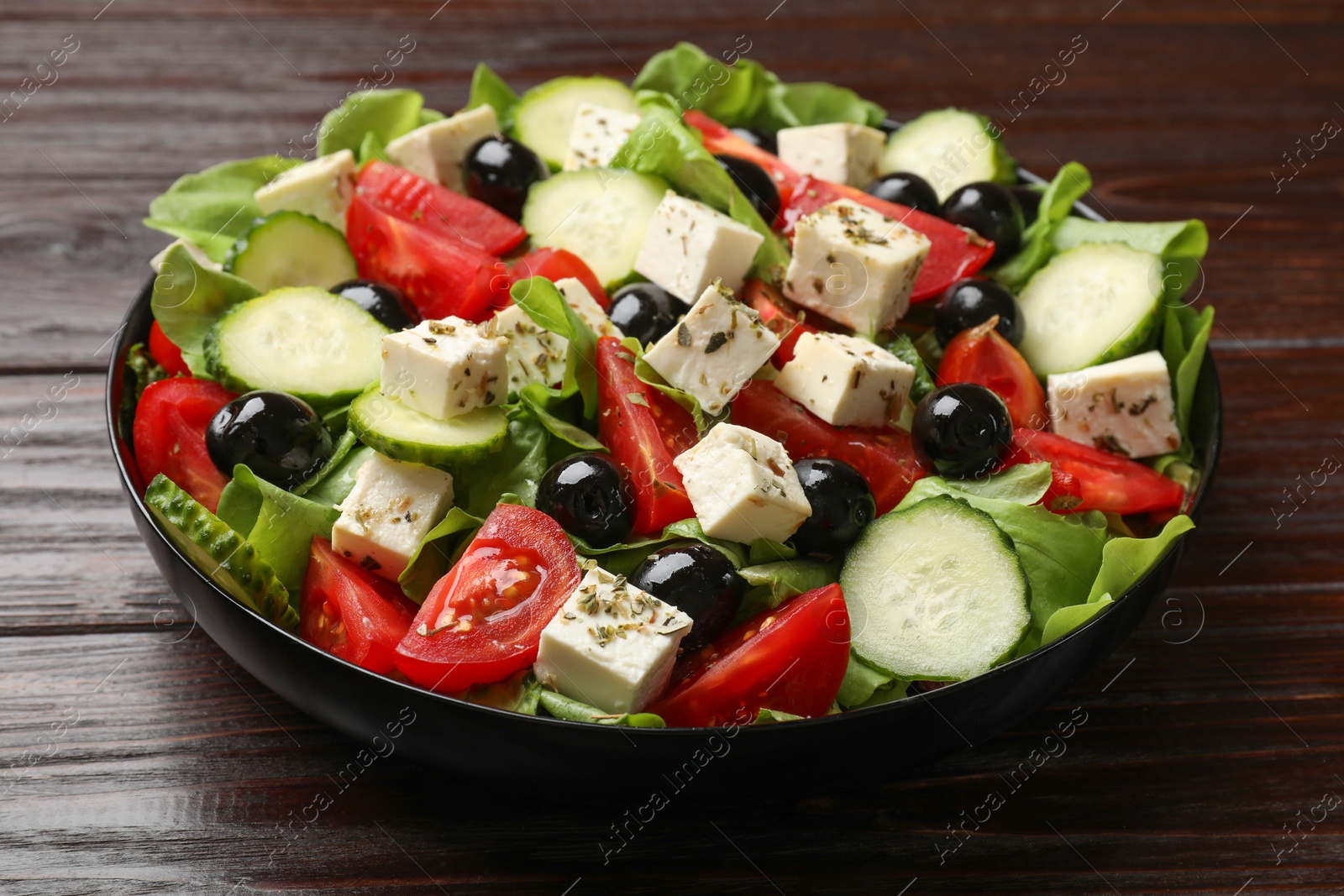 Photo of Delicious salad with feta cheese on wooden table, closeup