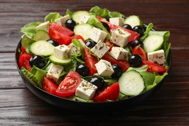 Photo of Delicious salad with feta cheese on wooden table, closeup