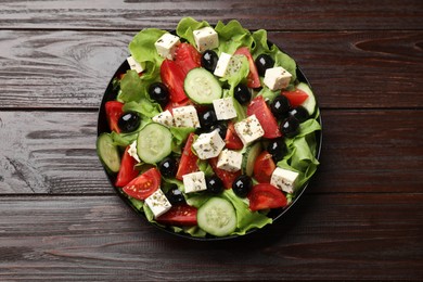 Photo of Delicious salad with feta cheese on wooden table, top view