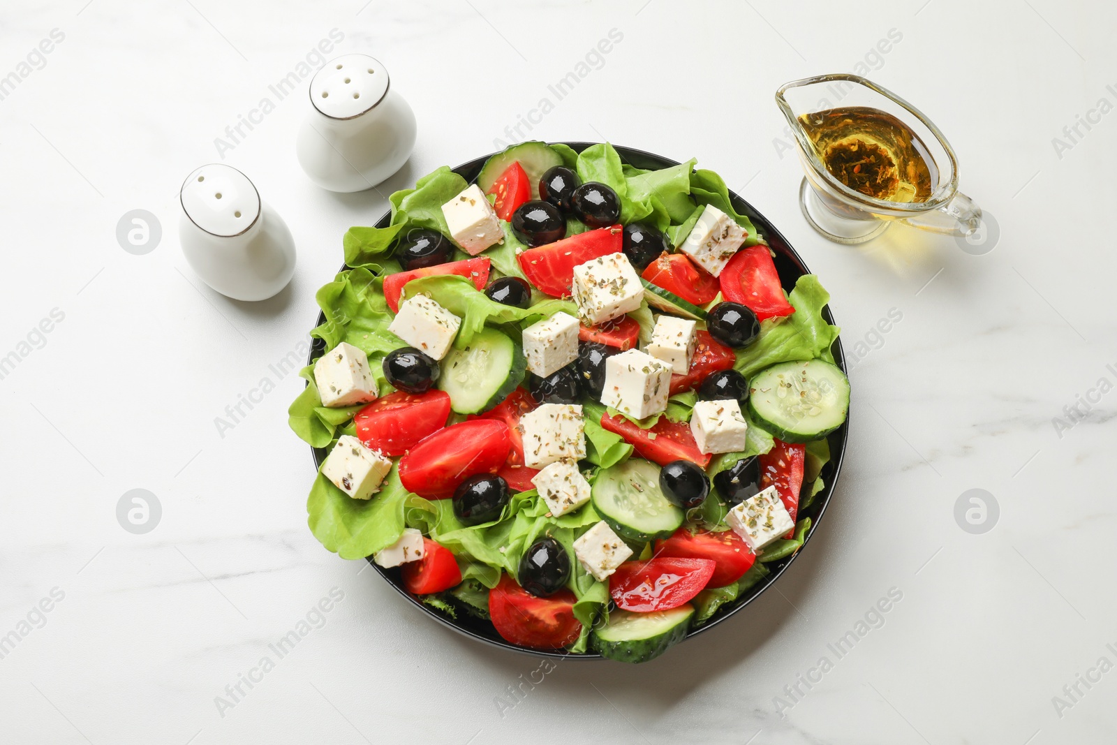 Photo of Delicious salad with feta cheese served on white marble table, top view