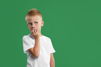 Photo of Scared little boy on green background. Space for text