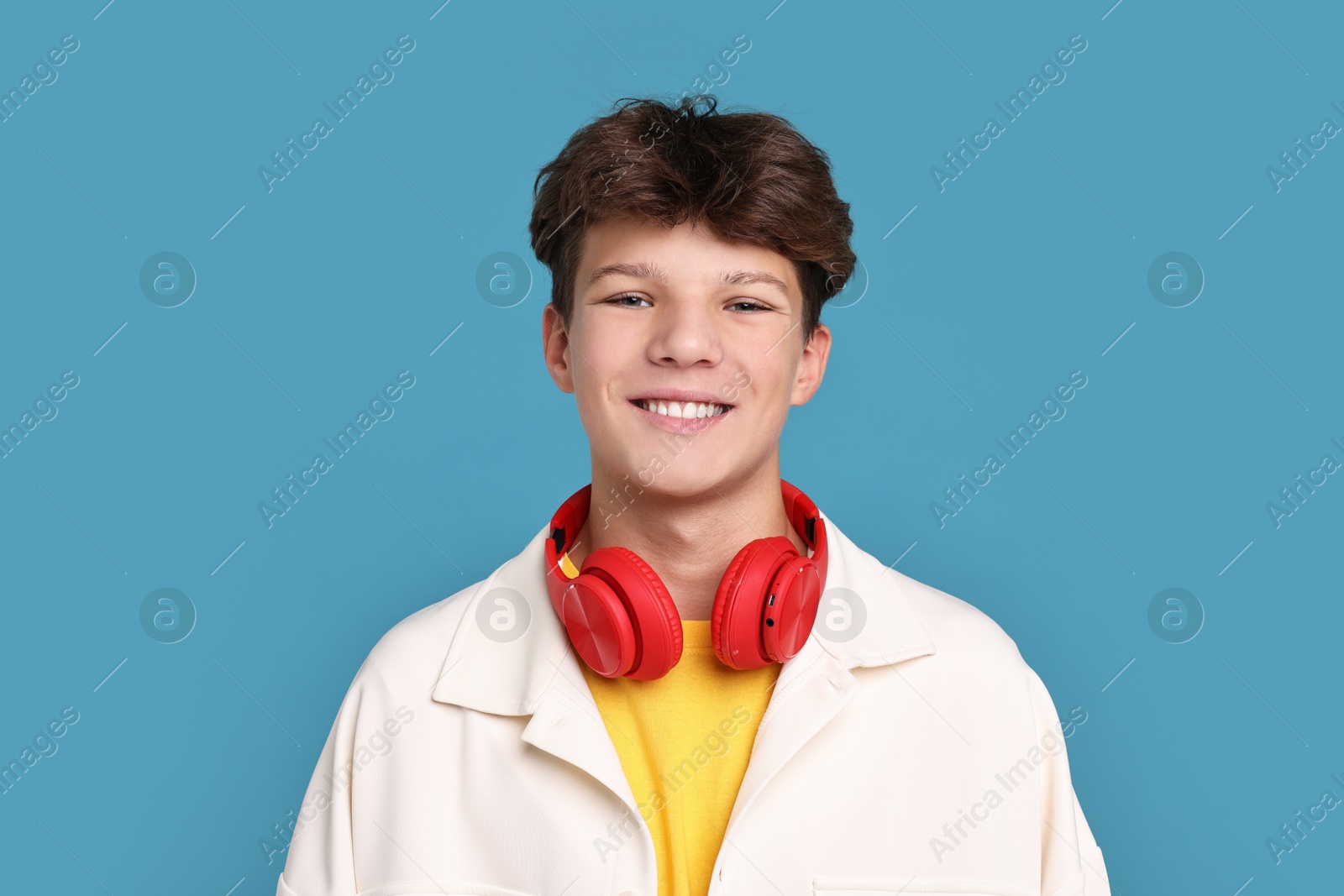 Photo of Happy teenage boy with headphones on light blue background