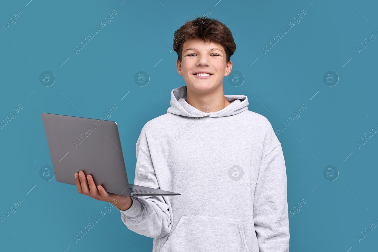 Photo of Teenage boy with laptop on light blue background