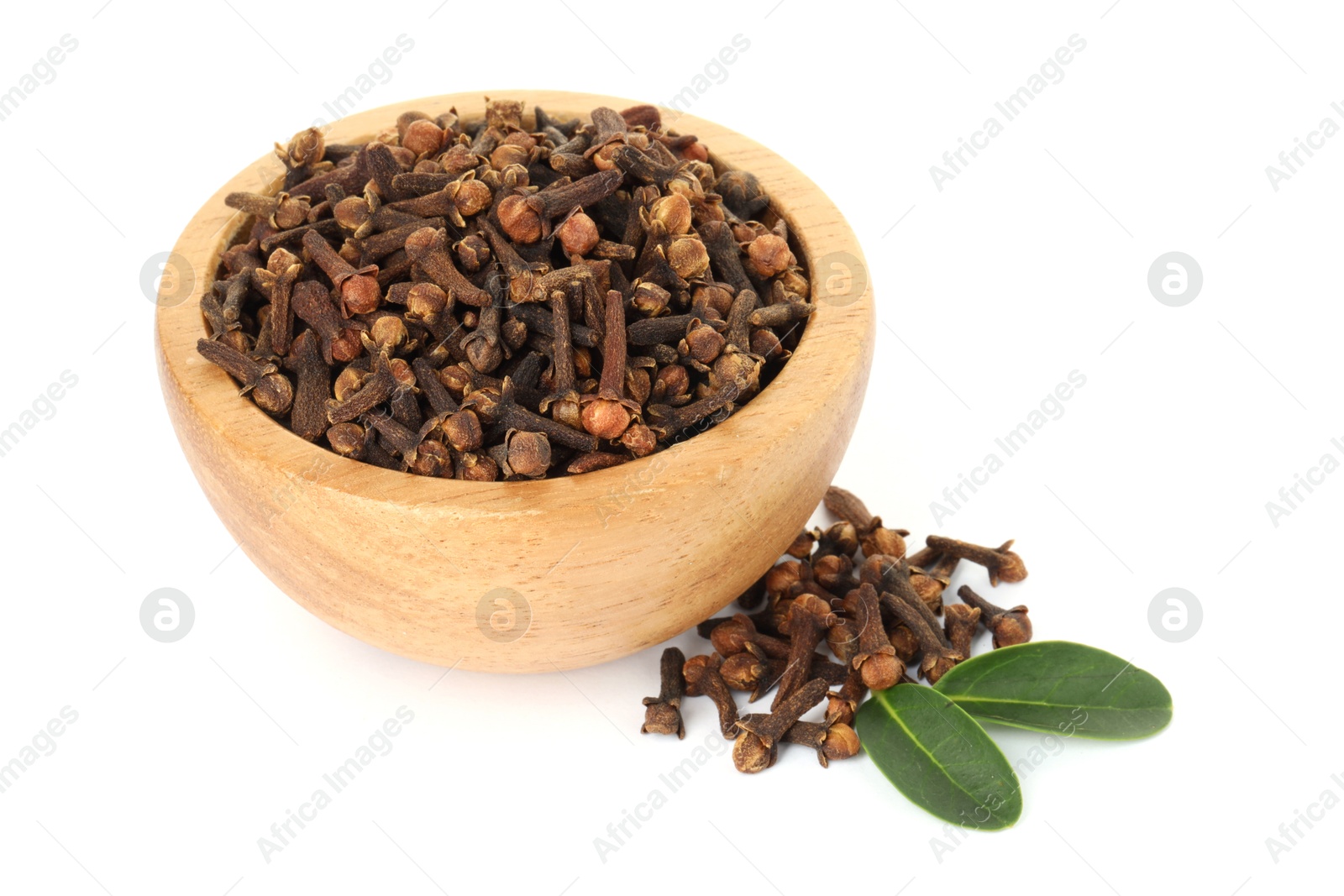 Photo of Dry clove buds in wooden bowl and green leaves on white background. Aromatic spice