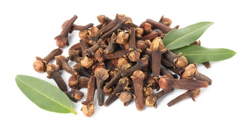 Photo of Pile of dry clove buds and green leaves on white background. Aromatic spice