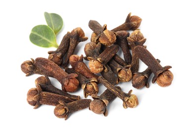 Photo of Pile of dry clove buds and green leaves on white background. Aromatic spice