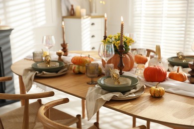 Stylish table setting with beautiful dishware, glasses and autumn decor in dining room