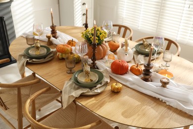 Stylish table setting with beautiful dishware, glasses and autumn decor in dining room