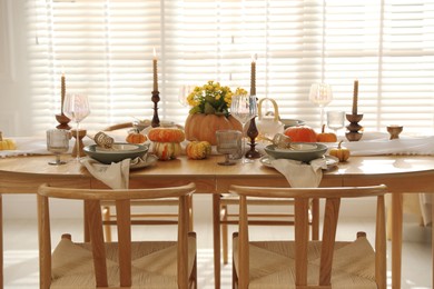 Stylish table setting with beautiful dishware, glasses and autumn decor in dining room