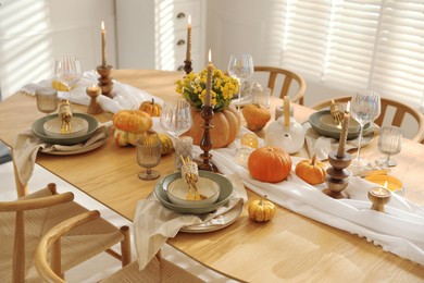 Stylish table setting with beautiful dishware, glasses and autumn decor in dining room