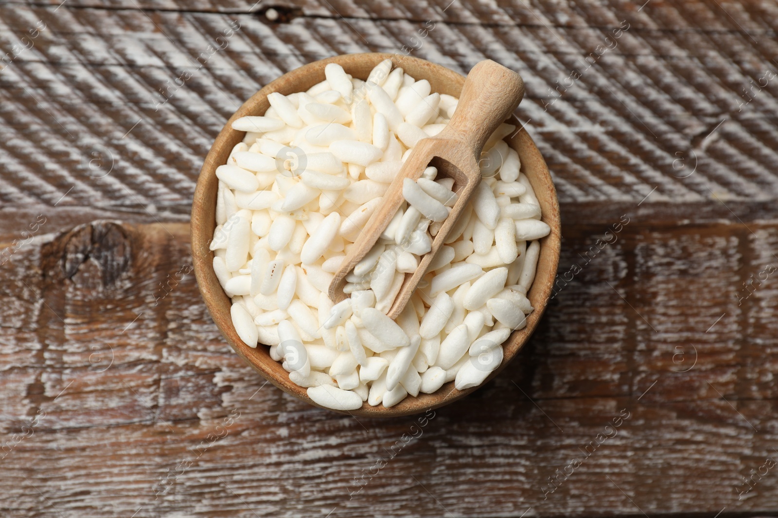 Photo of Puffed rice in bowl and scoop on wooden table, top view