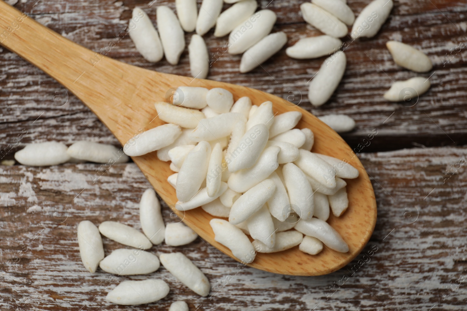 Photo of Puffed rice in spoon on wooden table, top view