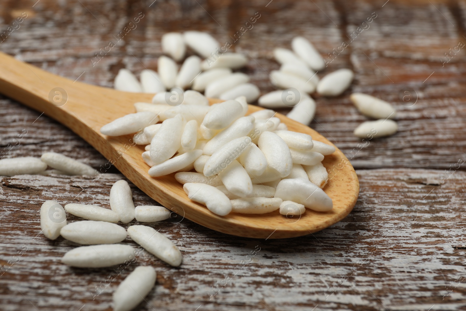 Photo of Puffed rice in spoon on wooden table, closeup