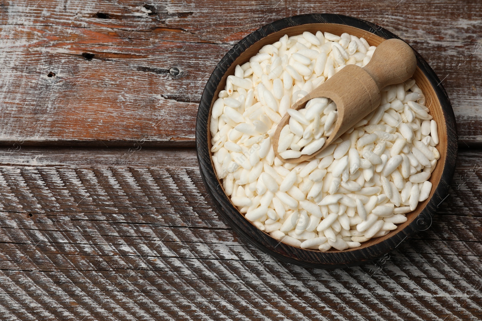 Photo of Puffed rice in bowl and scoop on wooden table, top view. Space for text