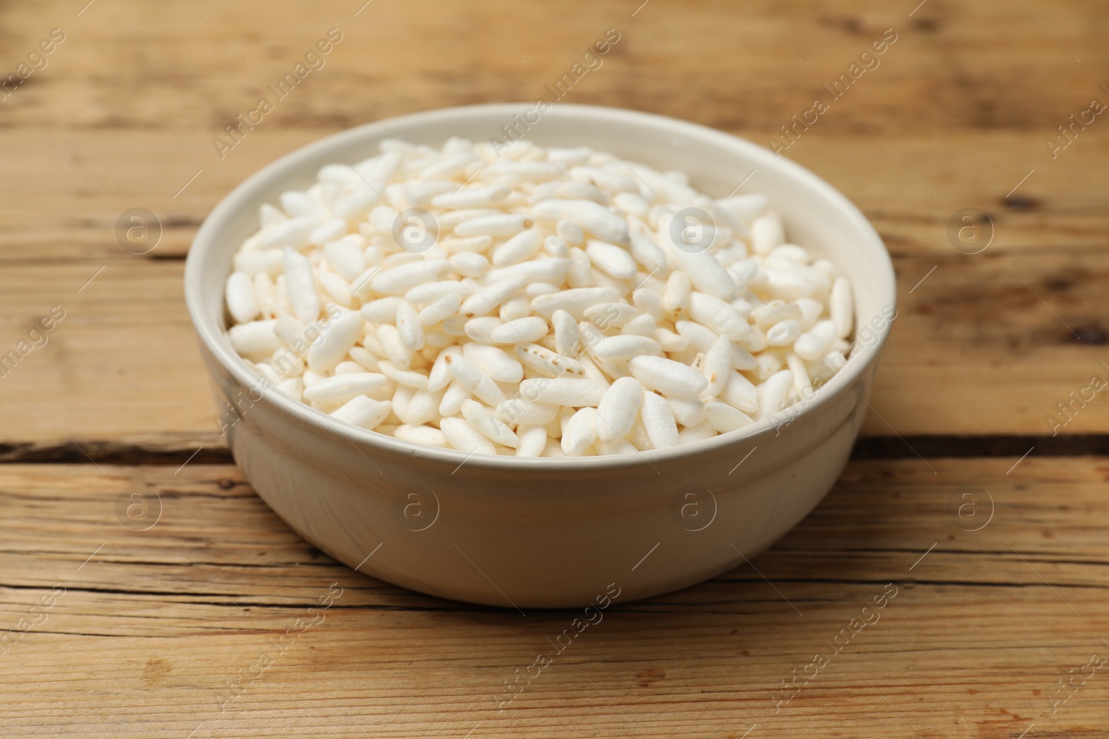 Photo of Puffed rice in bowl on wooden table, closeup