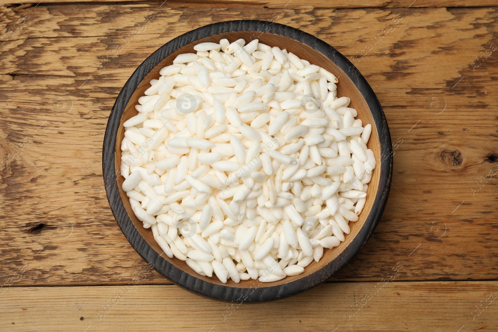 Photo of Puffed rice in bowl on wooden table, top view