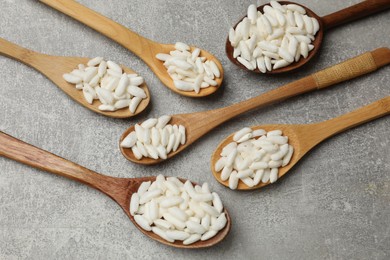 Photo of Puffed rice in wooden spoons on light grey table, above view