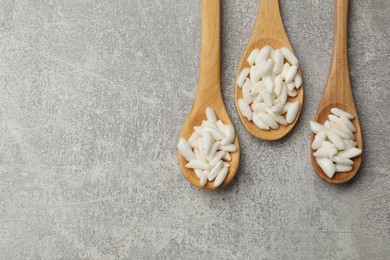 Photo of Puffed rice in wooden spoons on light grey table, flat lay. Space for text