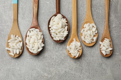 Photo of Puffed rice in wooden spoons on light grey table, flat lay