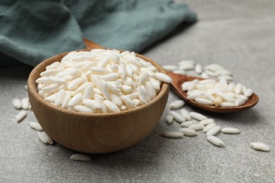 Photo of Puffed rice in bowl and spoon on light grey table, closeup