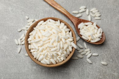 Photo of Puffed rice in bowl and spoon on light grey table, flat lay